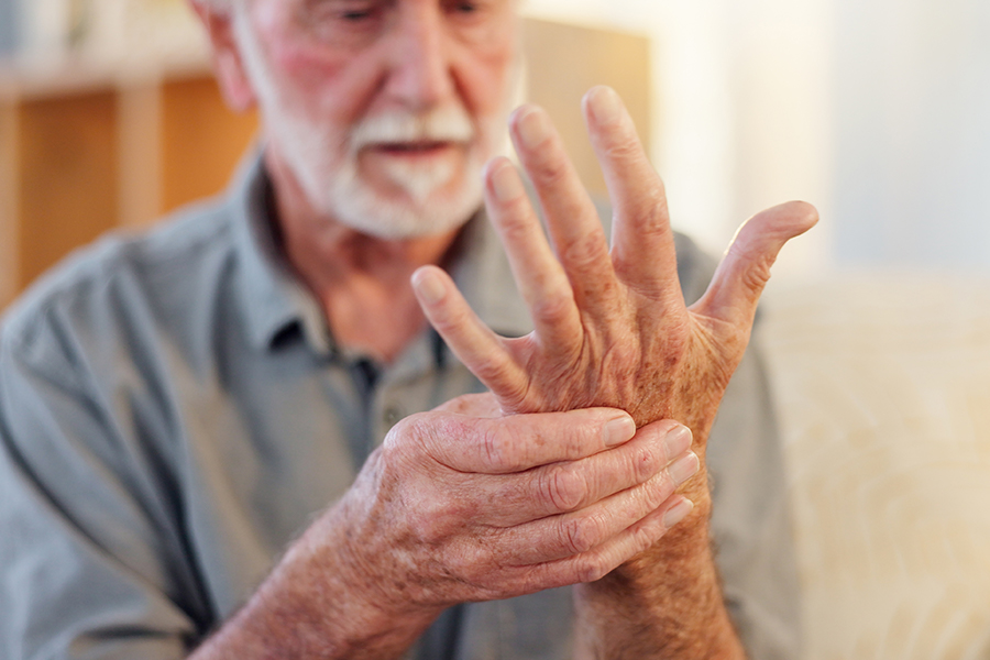 Mann schaut seine schmerzende Hand an