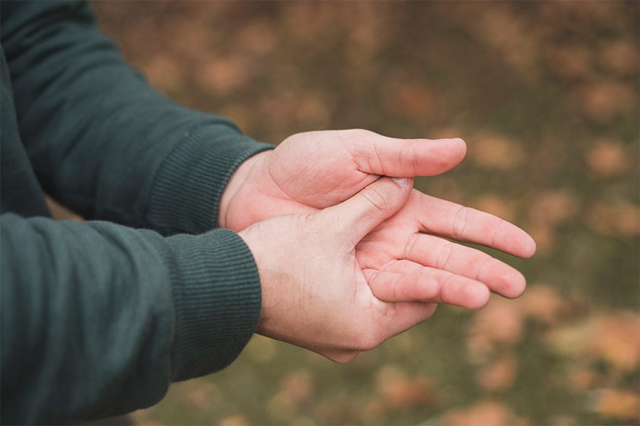 Mann drückt seinen Daumen auf seine schmerzende Hand